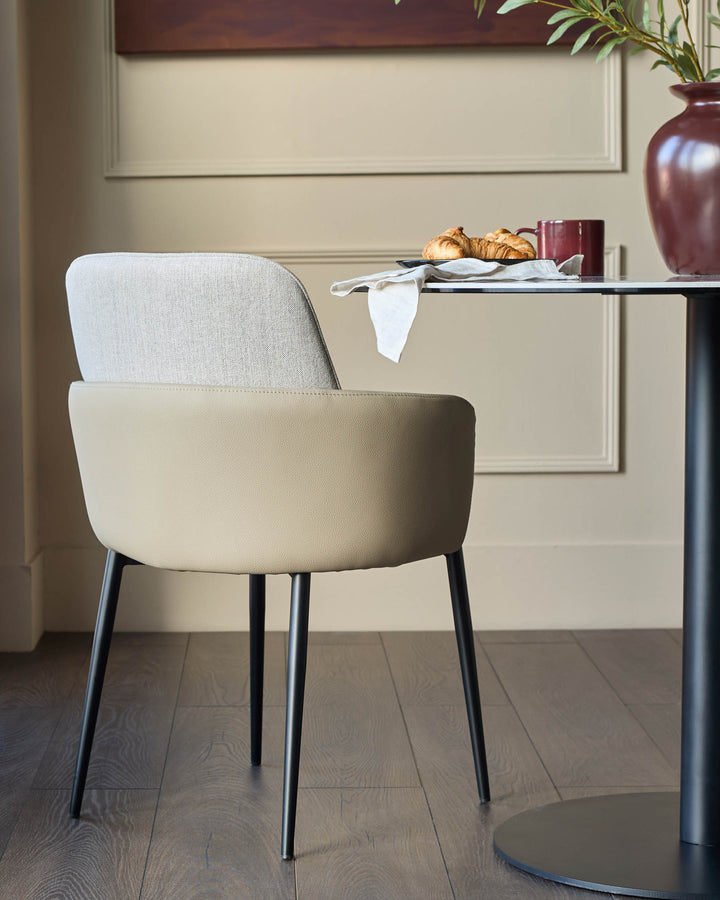 Wren dining chair in natural faux leather with light Grey fabric backrest and black metal legs, shown in a styled room setting.