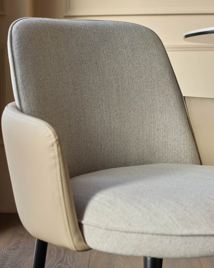 Wren dining chair in natural fabric and faux leather, shown at an angle highlighting the curved backrest and seat cushion.