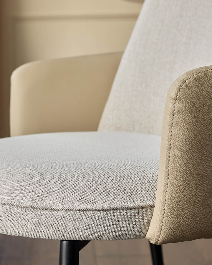 Wren dining chair in natural fabric and faux leather, angled side view showing seat cushion and curved armrest detail.