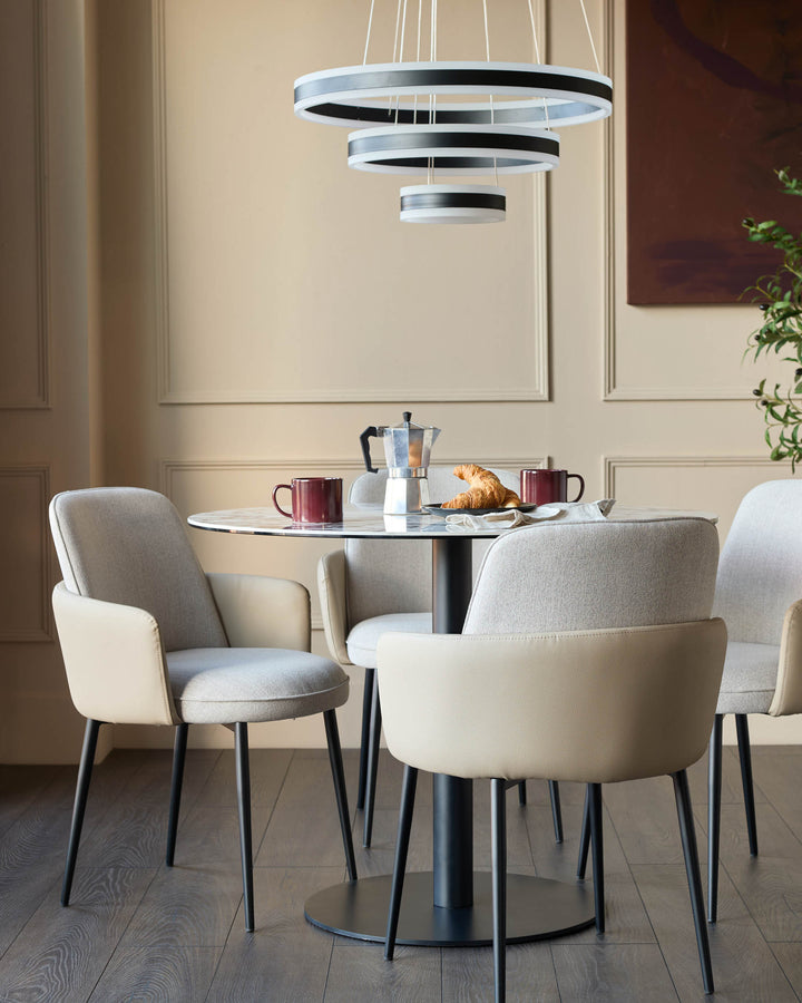 Wren dining chair in natural fabric and faux leather, shown in a modern dining setting with round table and pendant lights.