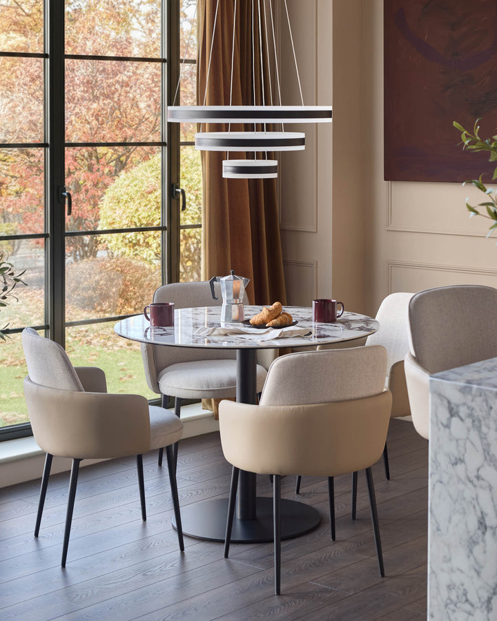 Wren dining chair in natural fabric, shown in a modern dining room setting around a marble table.