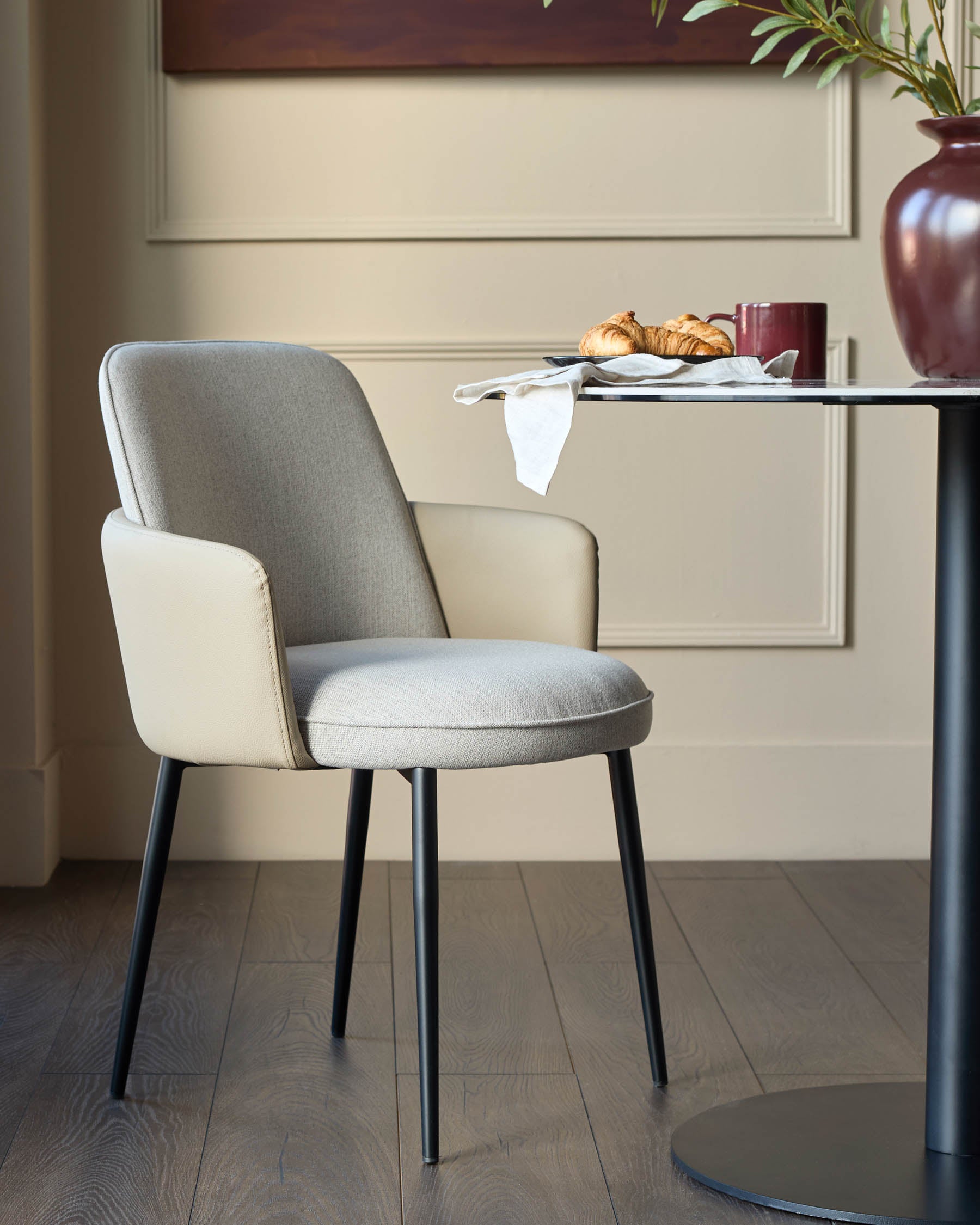 Wren dining chair in natural fabric and faux leather, featuring Grey upholstery, black tapered legs, and curved armrests.