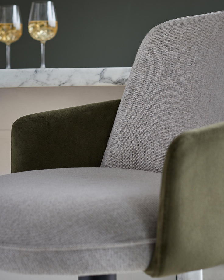 A stylish upholstered chair in muted grey and olive green. Ideal for adding a touch of modern elegance to any dining space.