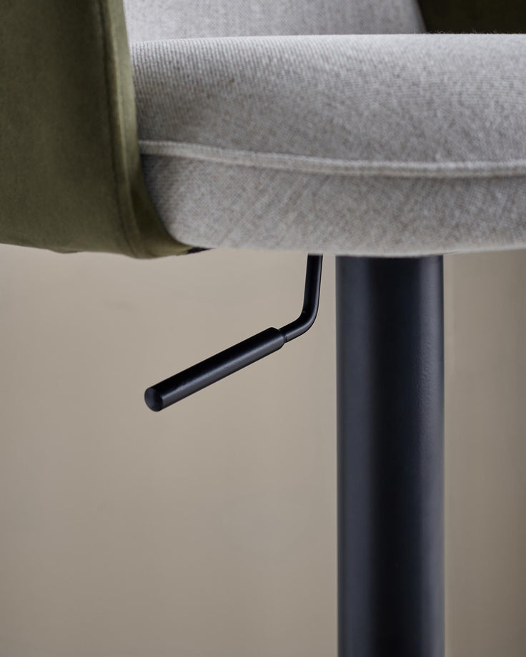 Close-up of a grey and green bar stool with a black stand and lever, showcasing its adjustable height feature.