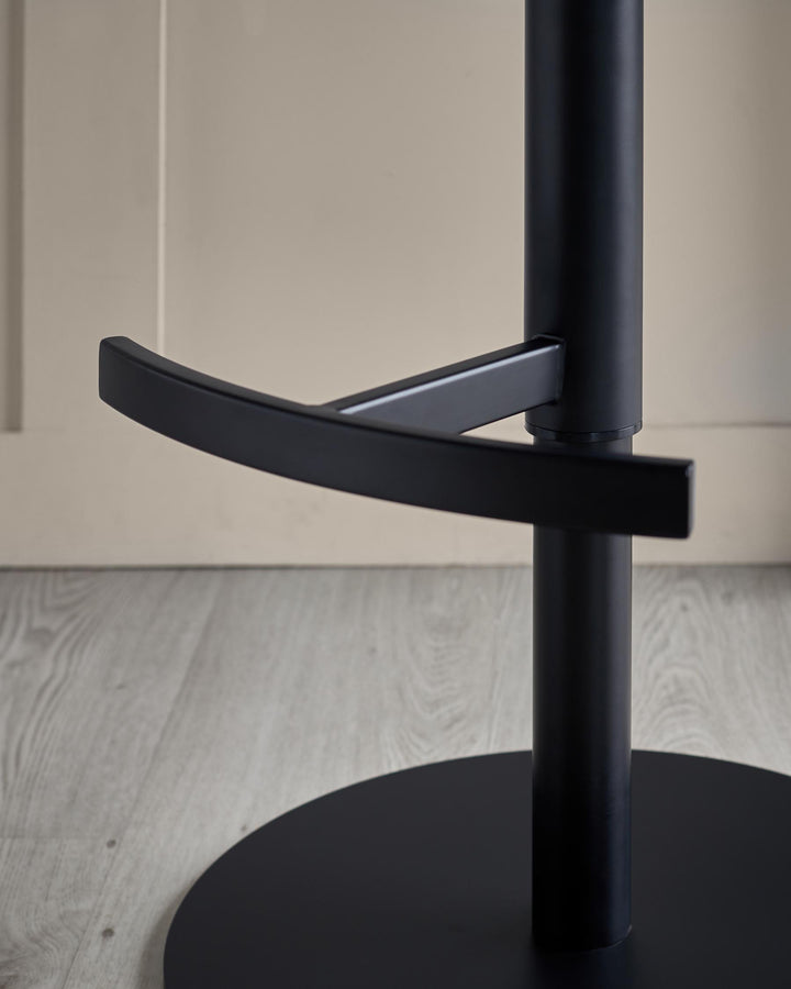 Close-up of a sleek, modern black bar stool with a round base and footrest, set against a neutral background.