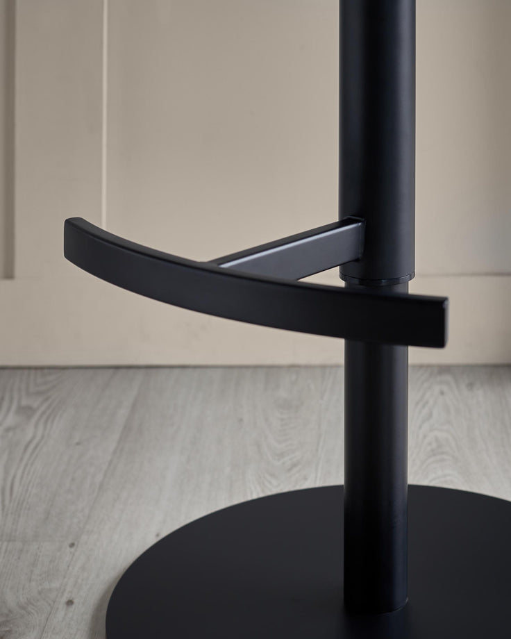 Close-up of a sleek, modern black bar stool with a round base and footrest, set against a neutral background.