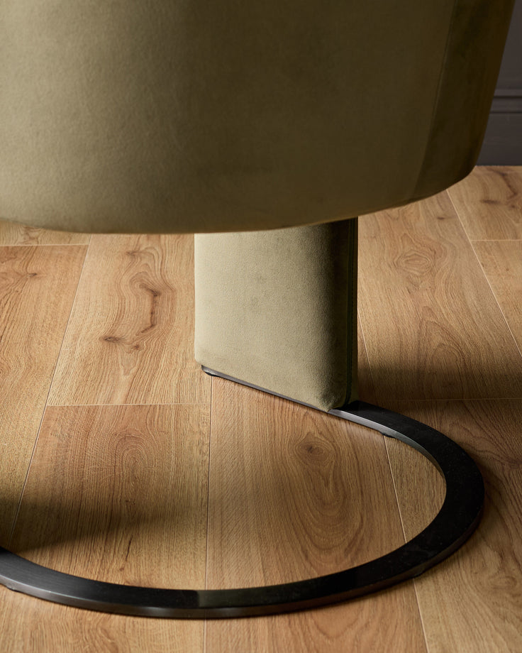 Wren cantilever dining chair with olive-green fabric seat and natural upholstered back, black metal base, floor-level view.