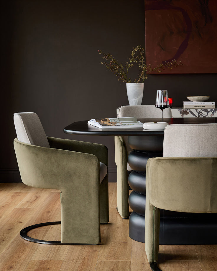 Wren cantilever dining chair in natural and olive green velvet, shown in a styled dining setting with black table.