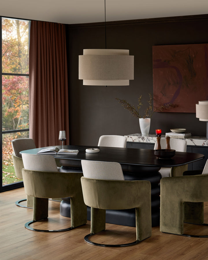 Wren cantilever dining chair in natural and olive green velvet, shown in a modern dining room setting.