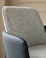 Wren dining chair detail showing grey fabric backrest and black faux leather seat with stitched edging.