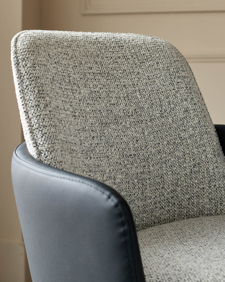 Wren dining chair detail showing grey fabric backrest and black faux leather seat with stitched edging.