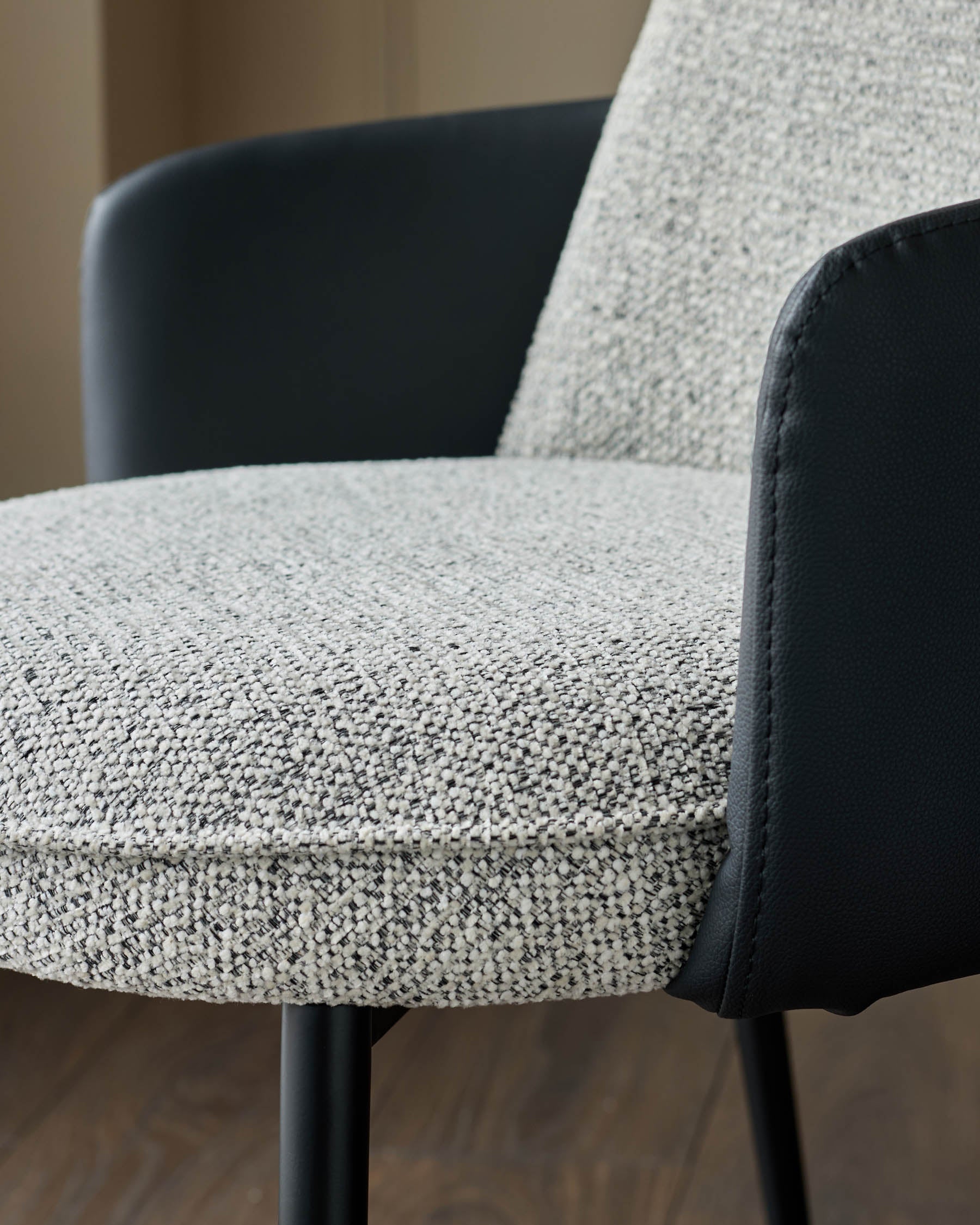 Wren dining chair close-up showing grey fabric seat and black faux-leather backrest and armrests.