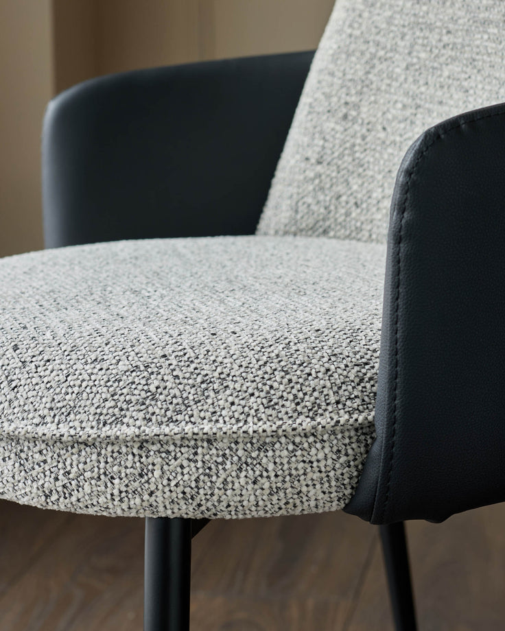 Wren dining chair close-up showing grey fabric seat and black faux-leather backrest and armrests.
