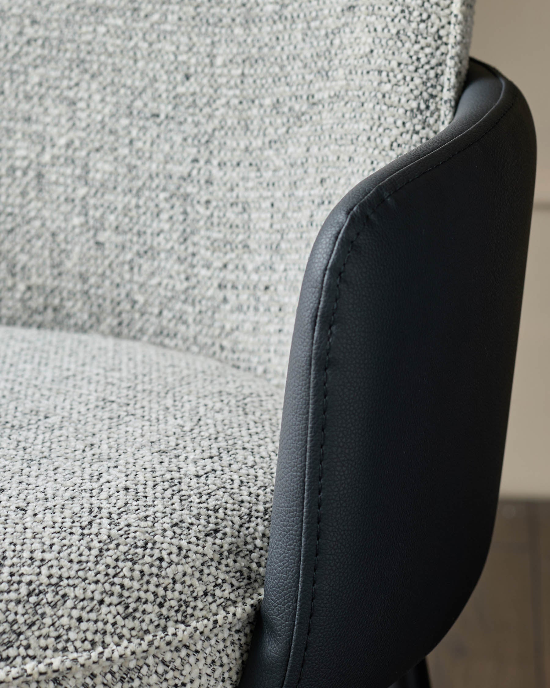 Wren dining chair showing grey fabric seat with black faux leather armrest and curved edge detail.