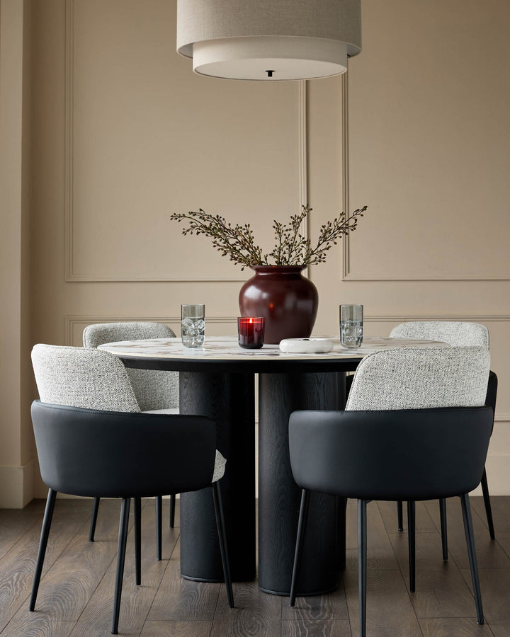 Wren dining chair in grey fabric and black faux leather, shown in a styled dining room setting with round table.