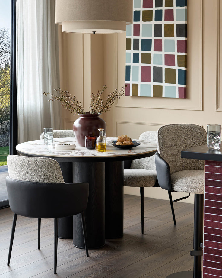 Wren dining chair in grey fabric and black faux leather, shown in a modern dining setting with round table.