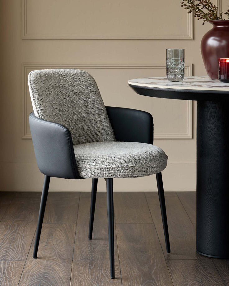 Wren dining chair in grey fabric and black faux leather with black legs, shown beside a round black pedestal table.