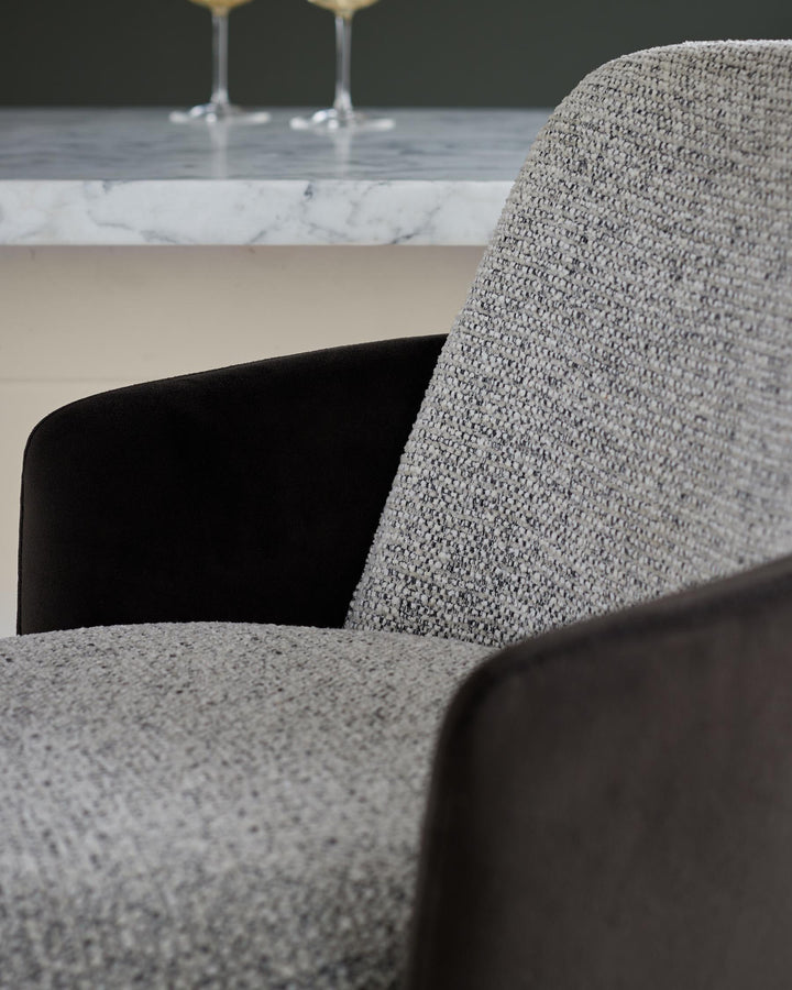Close-up of a textured grey chair with dark brown armrests, showcasing quality craftsmanship and modern design.