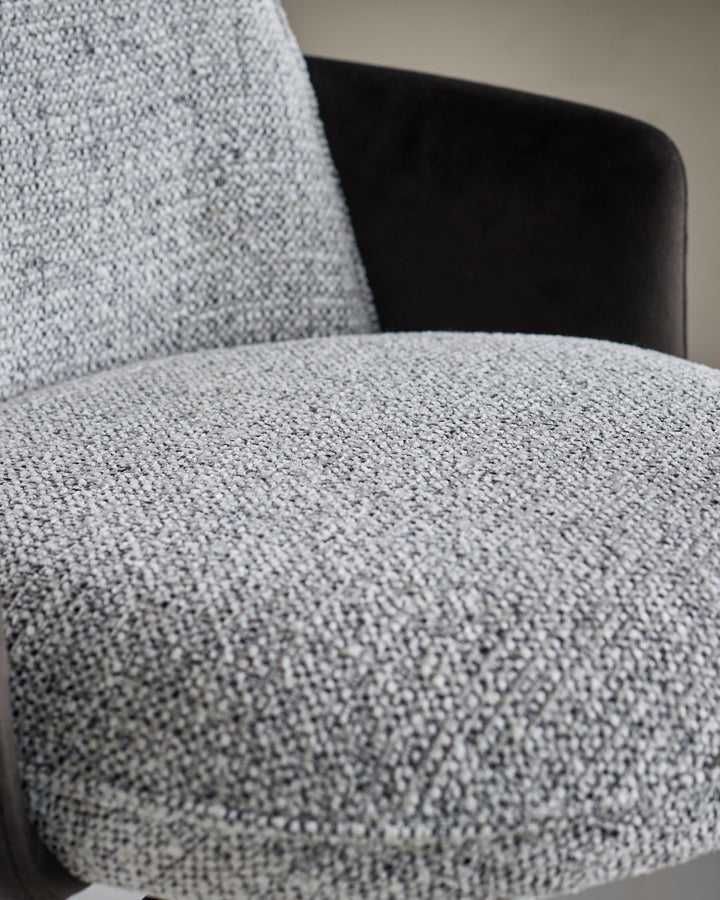 Close-up of a stylish chair featuring textured grey fabric and dark brown frame, offering comfort and a contemporary design.
