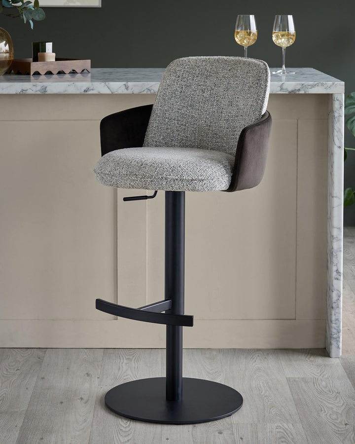 A stylish grey and brown bar stool with a black stand in front of a kitchen counter with two glasses of white wine.