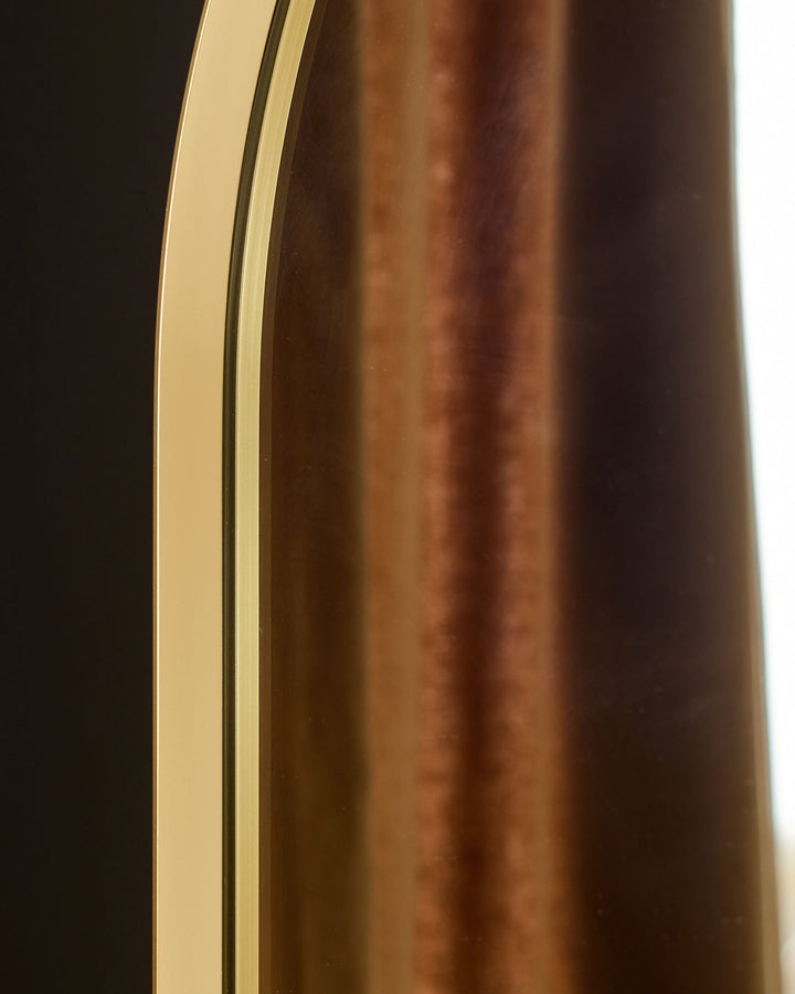 Gold arch wall mirror with curved frame and polished finish, side profile view