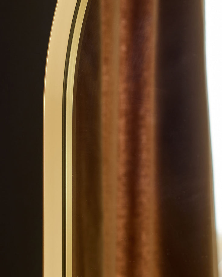 Gold arch wall mirror with curved frame and polished finish, side profile view