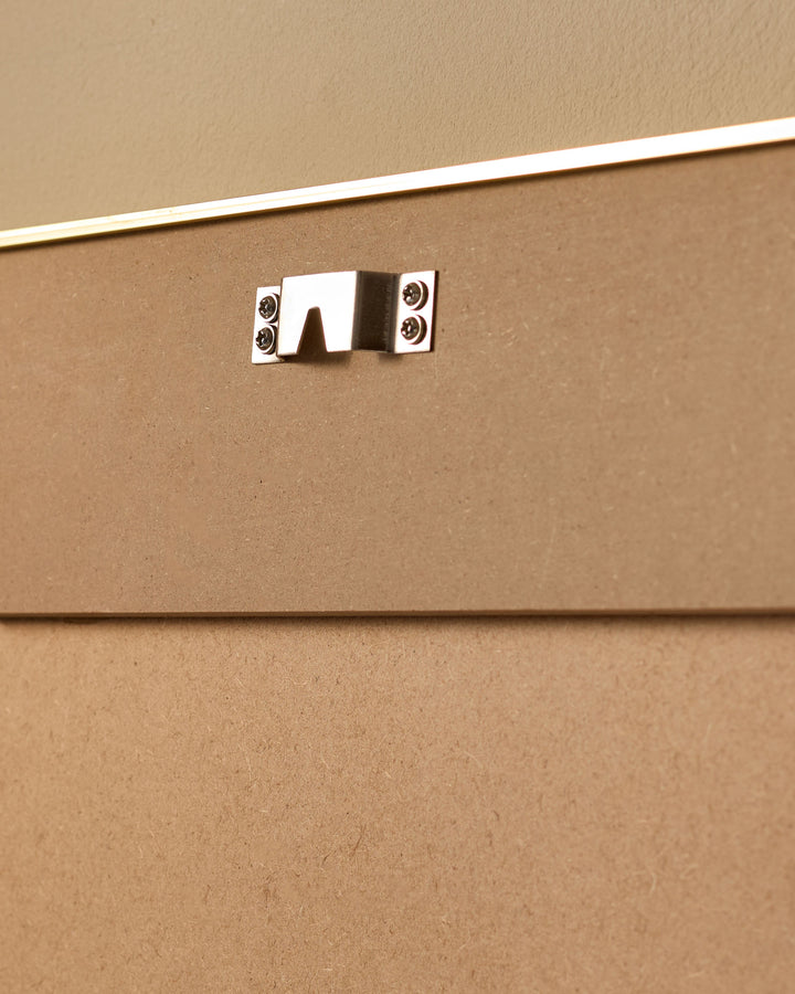 Close-up of polished chrome handle on tan upholstered furniture panel with white trim detail.