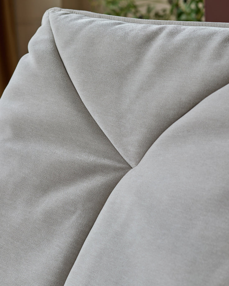 Zia swivel chair in natural grey fabric, close-up detail showing soft upholstery texture and curved seaming.