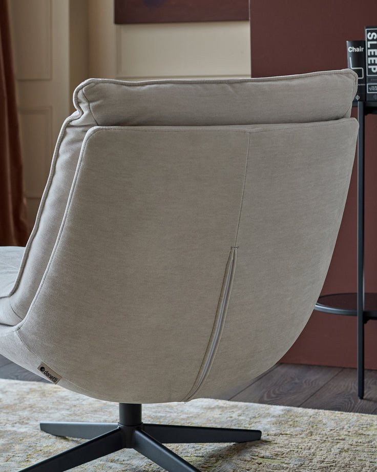 Rear view of Zia swivel chair in natural grey fabric, showing curved back and black star base on area rug.