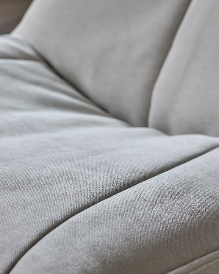 Close-up of natural grey fabric on Zia swivel chair, showing soft upholstery texture and curved seating detail.