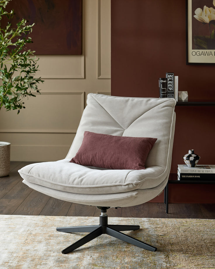 Zia swivel chair in natural grey fabric with burgundy accent pillow, black swivel base, angled front view in styled room setting.