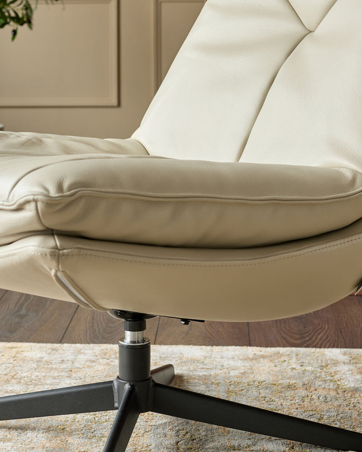 Cream leather swivel chair with padded armrests and high backrest, featuring a black metal base on a neutral area rug.