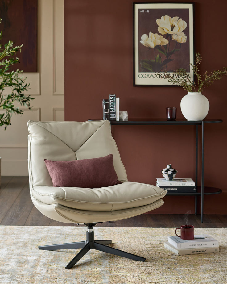 Cream leather swivel chair with curved back and padded seat on black metal base, styled in modern living room.