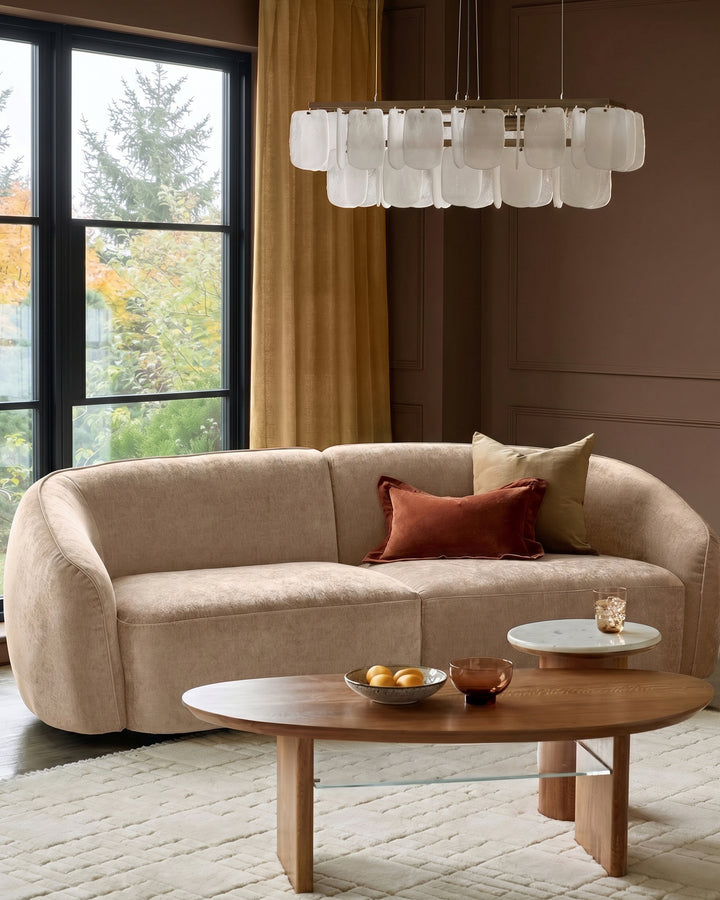 Champagne fabric 3-seater sofa with curved arms and rounded silhouette, styled in a modern living room setting.