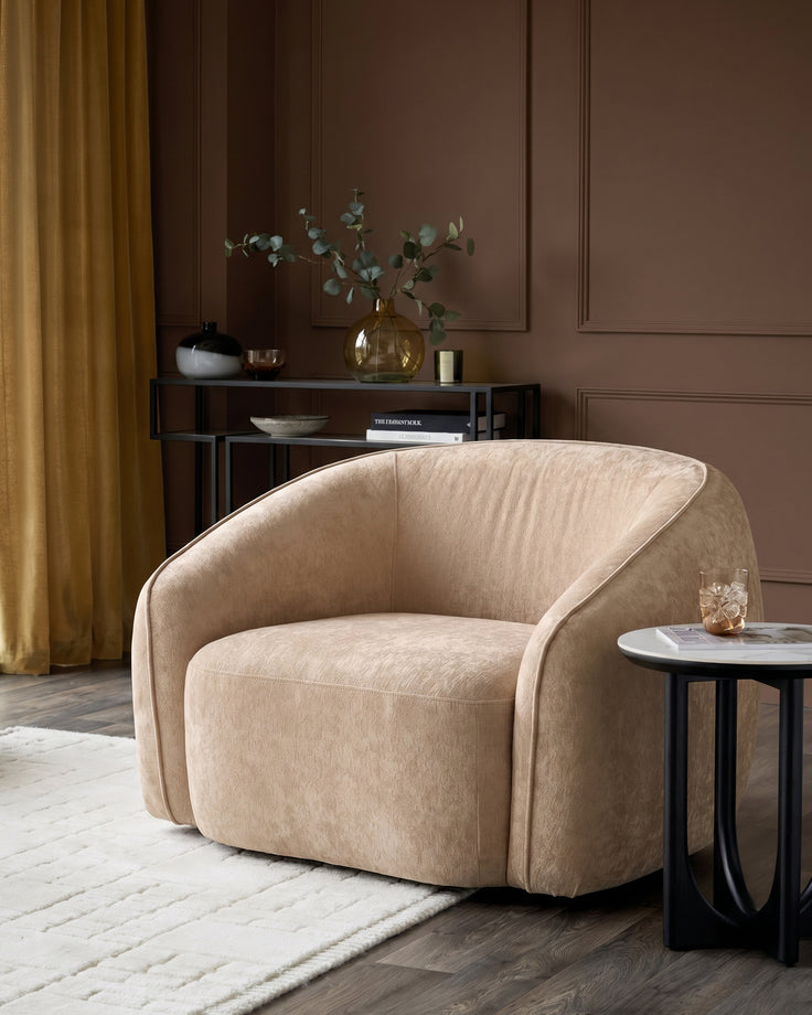 Zoey armchair in champagne fabric with curved design, displayed in a modern living room setting.