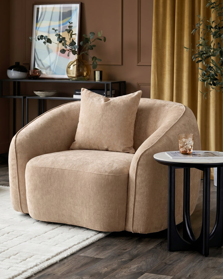 Champagne fabric Zoey armchair with curved design, shown in a styled living room setting with accent pillow and side table.