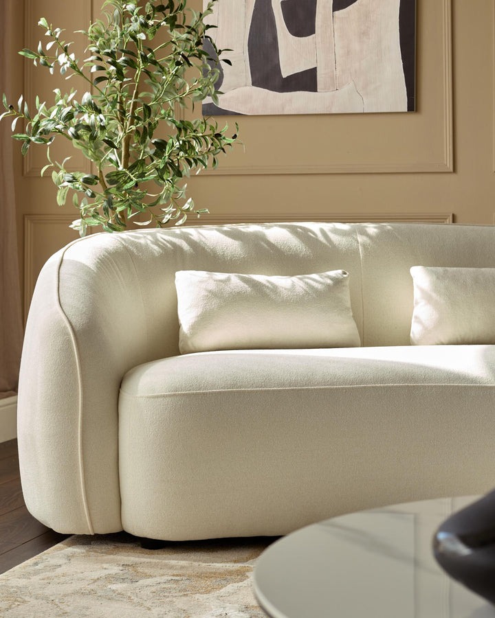 A modern curved sofa with scatter cushions, complemented by a stylish coffee table and understated decor.
