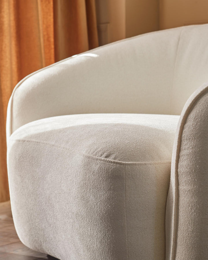 Close-up of a stylish white armchair with textured fabric, suggesting comfort and modern design.