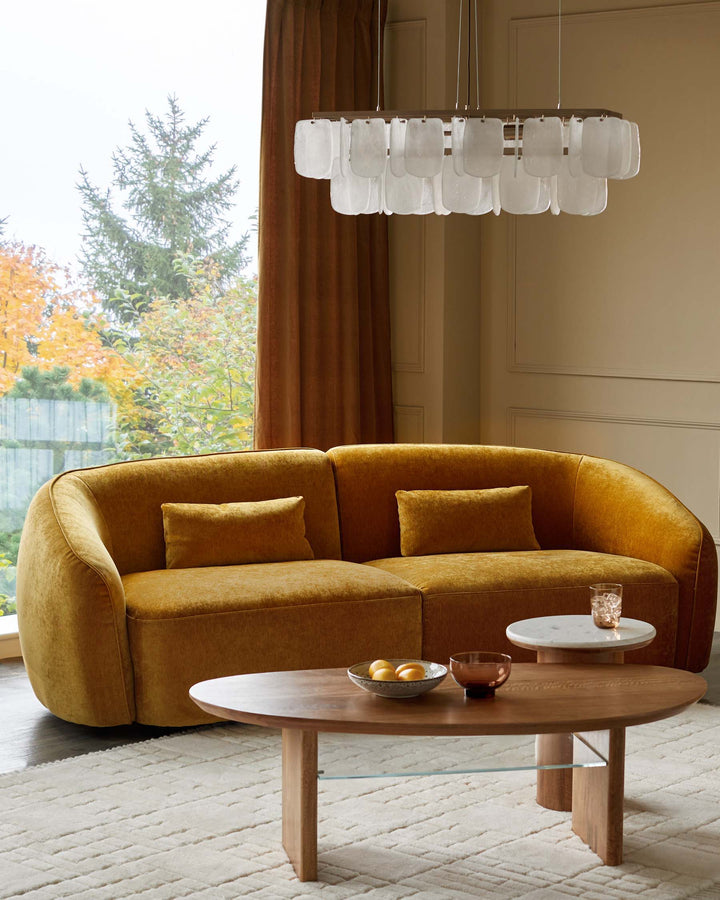 A stylish living room featuring a mustard-yellow sofa, coffee tables and a modern chandelier.