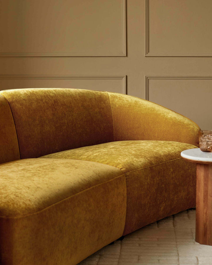 Stylish mustard velvet sofa paired with a modern side table, creating a warm and inviting living space.
