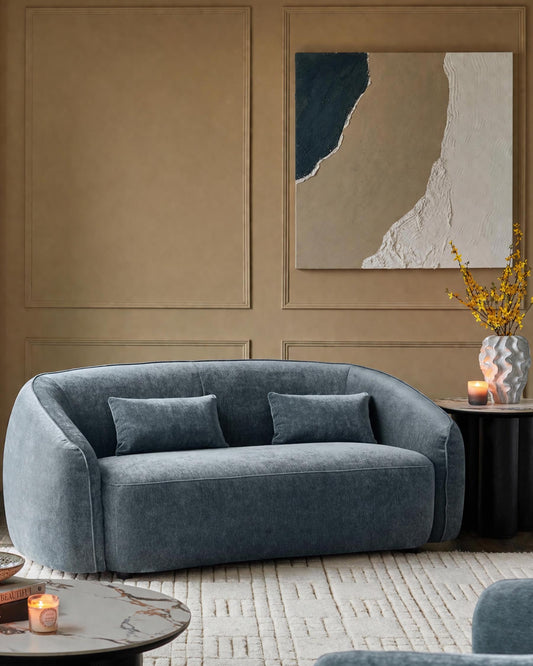 Zoey 2-seater sofa in blue-grey fabric with curved arms and two matching cushions in a neutral room setting.