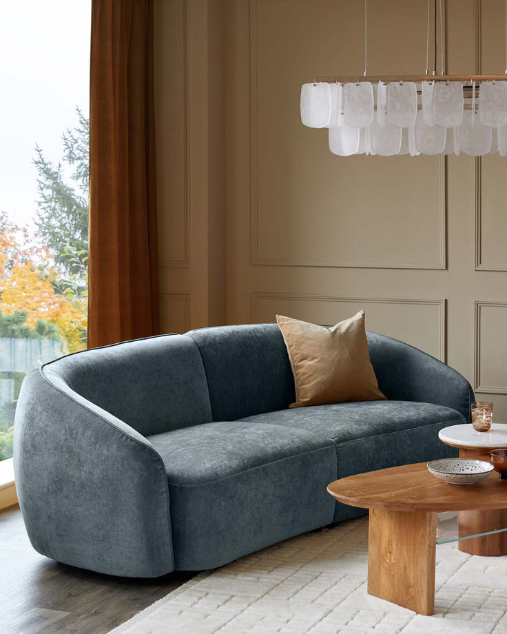 Stylish living room featuring a plush blue sofa, contemporary coffee tables, and a unique modern chandelier.