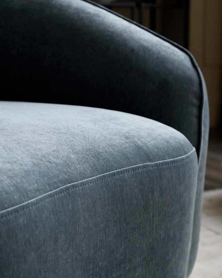 Close-up of a teal velvet chair. The stylish design and plush fabric make it a comfortable addition to any home.