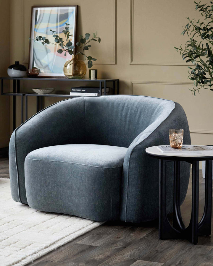Stylish blue armchair sits beside a black side table. Shelving unit and framed art in background. Modern interior design.
