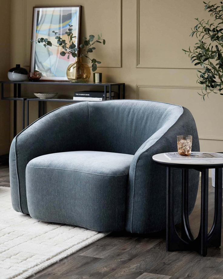 Stylish blue armchair sits beside a black side table. Shelving unit and framed art in background. Modern interior design.