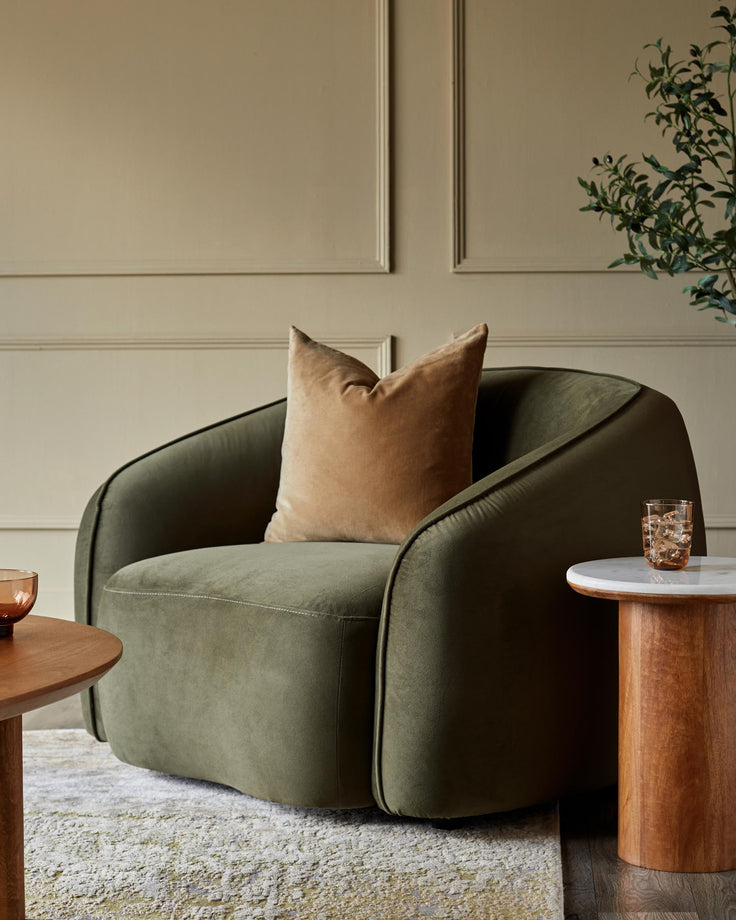A plush green armchair with a tan cushion and a marble-topped side table add style and comfort to any living space.