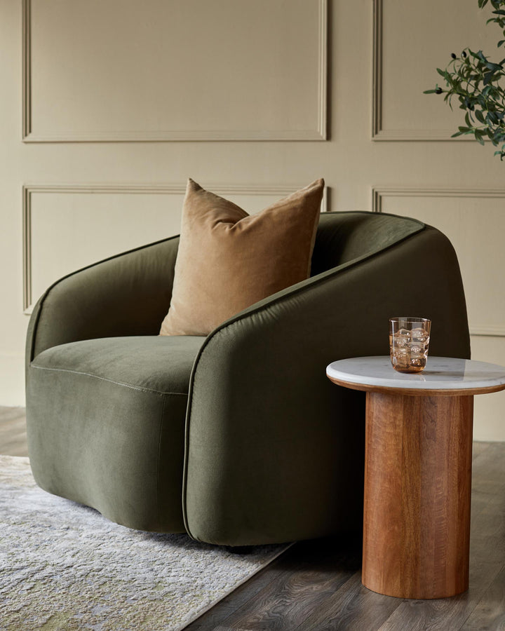 A stylish green armchair with a cushion, paired with a round side table. Contemporary furniture.