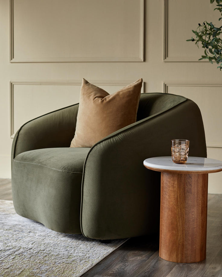 A stylish green armchair with a cushion, paired with a round side table. Contemporary furniture.