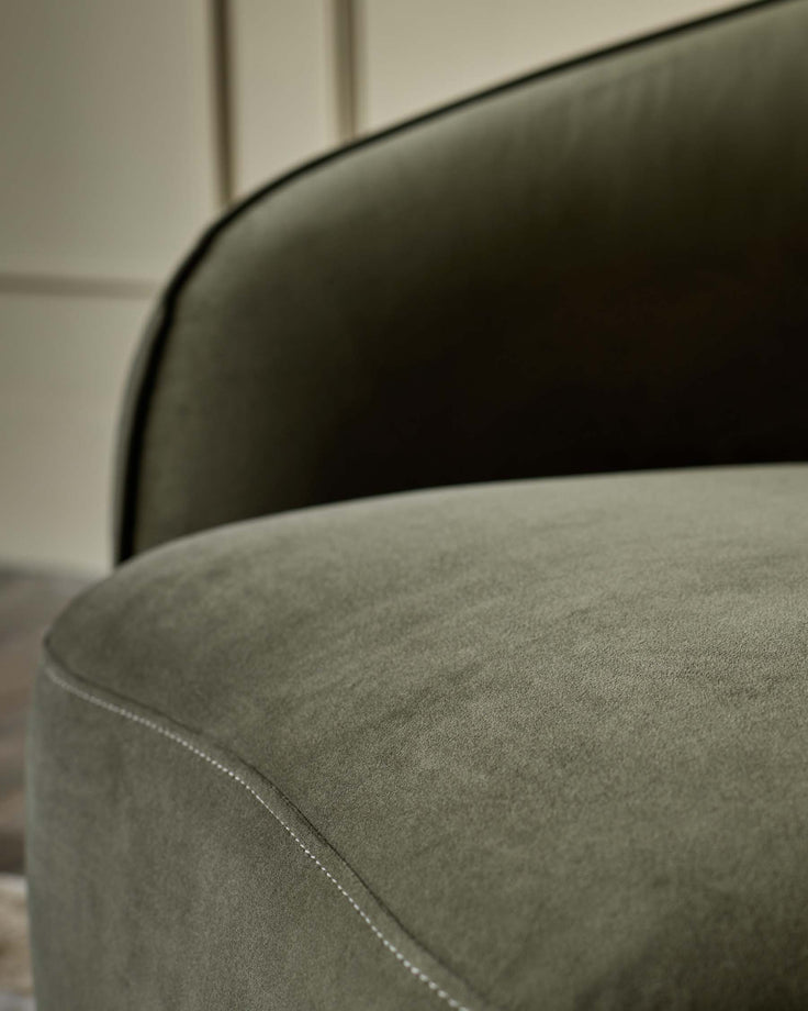 Close-up of a lush, olive-green velvet chair with detailed stitching. Luxurious comfort and classic design.
