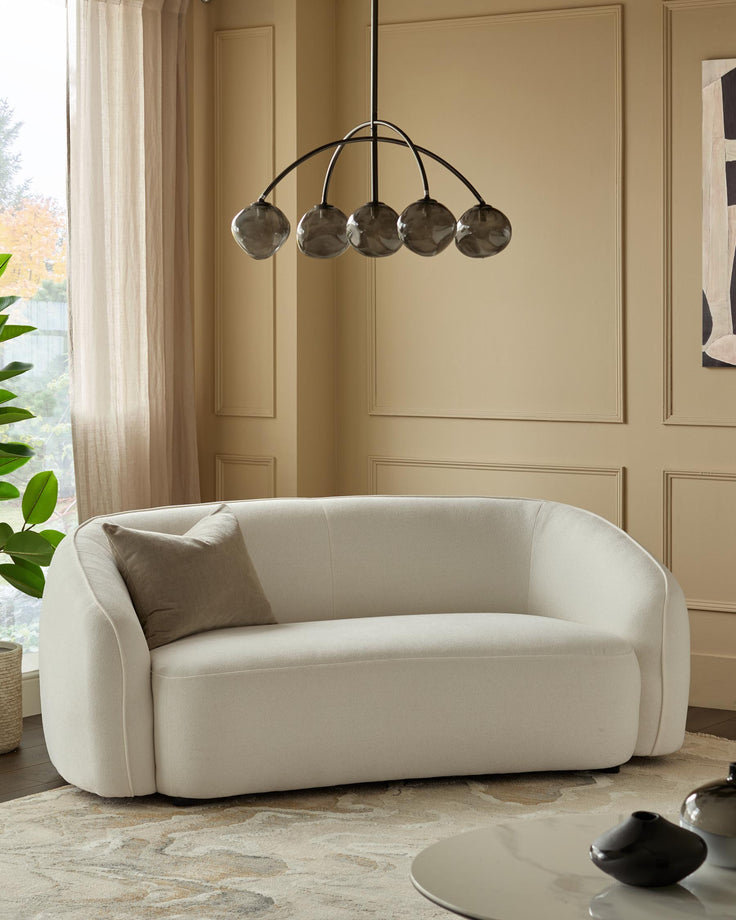 A neutral coloured room with a modern white loveseat sofa and a grey glass orb chandelier.